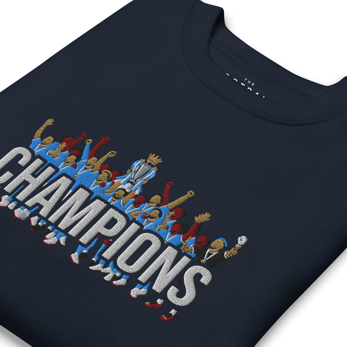 Folded angled view of Manchester City-inspired navy blazer sweatshirt with trophy-lift embroidery and CHAMPIONS lettering